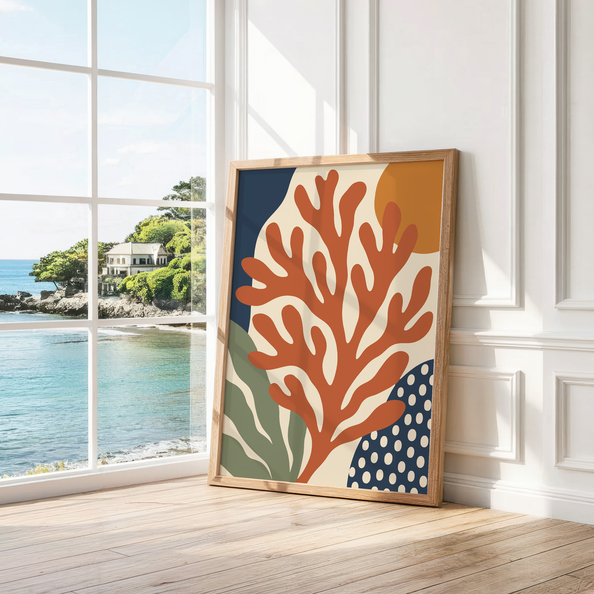 Rust red branching coral print leaning by a bright window with a sea view