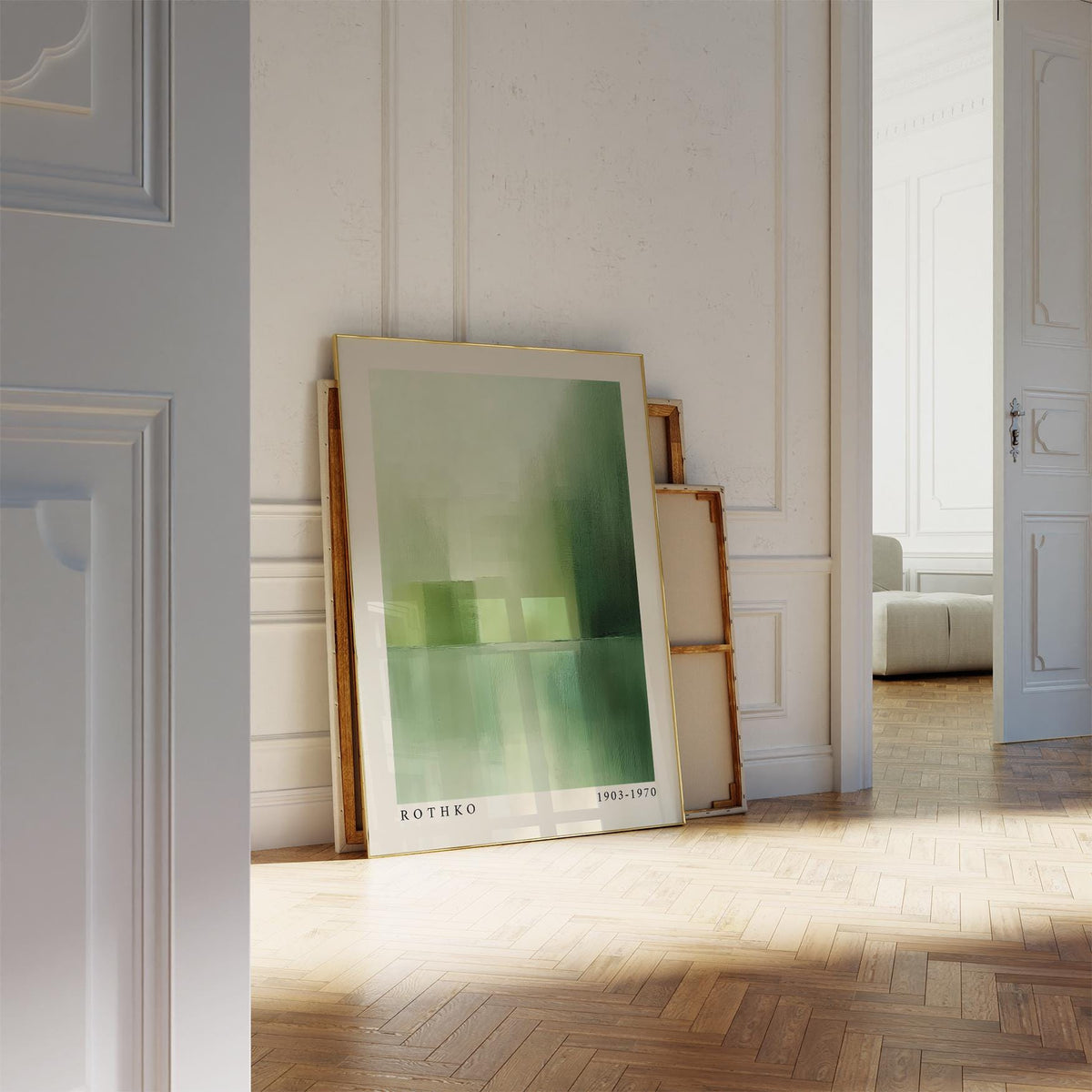 Green abstract wall art leaning on floor with wooden frames behind in a bright room