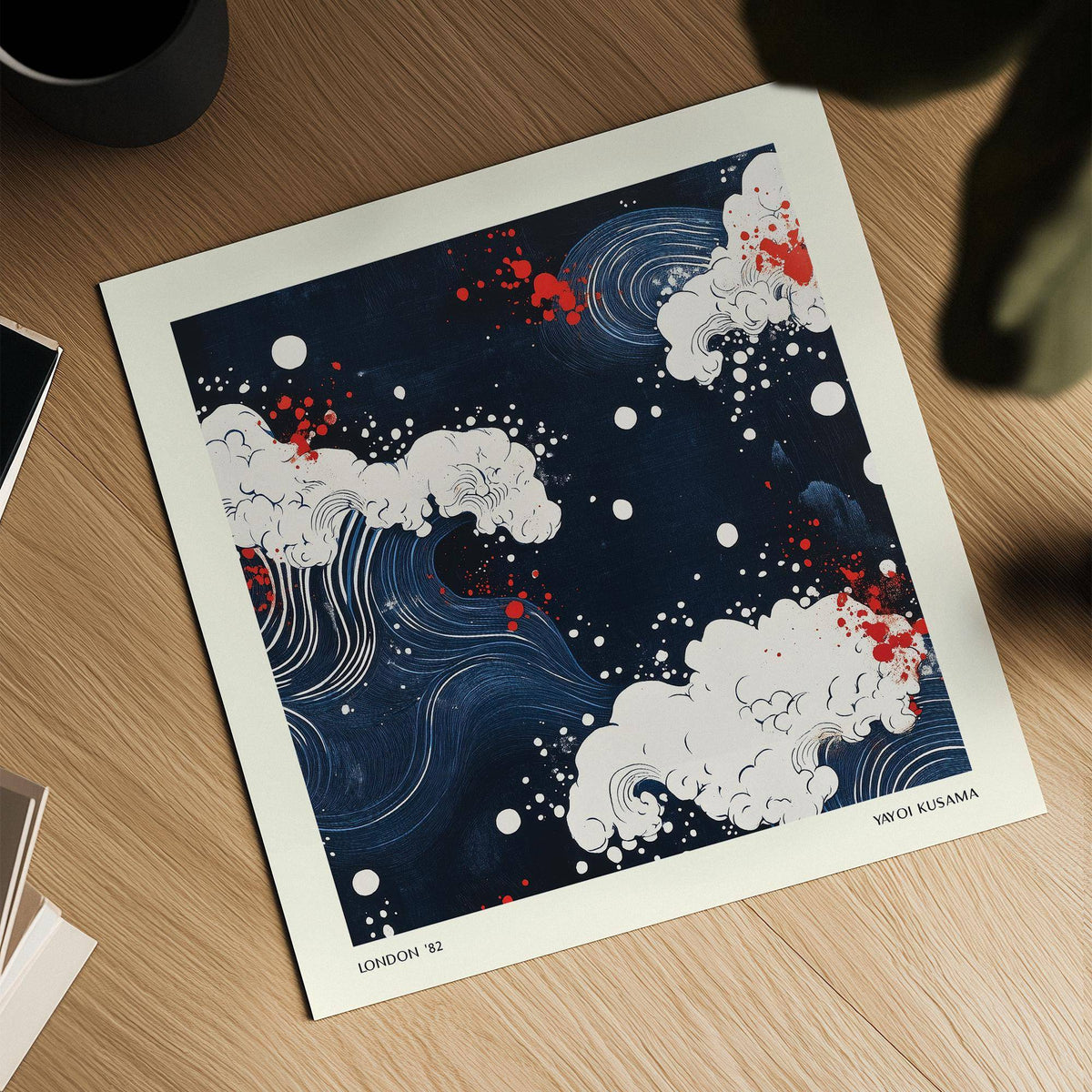 Japanese Art close-up of stylized white waves with red dots against a dark blue background on a wooden surface with a black cup nearby