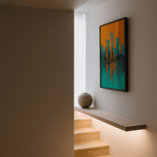 Modern skyline poster in orange and turquoise hanging on a grey wall above a wooden shelf with a round ceramic vase