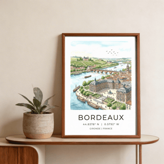 Framed Bordeaux City Art print with green vineyards and a river beside a potted plant on a table