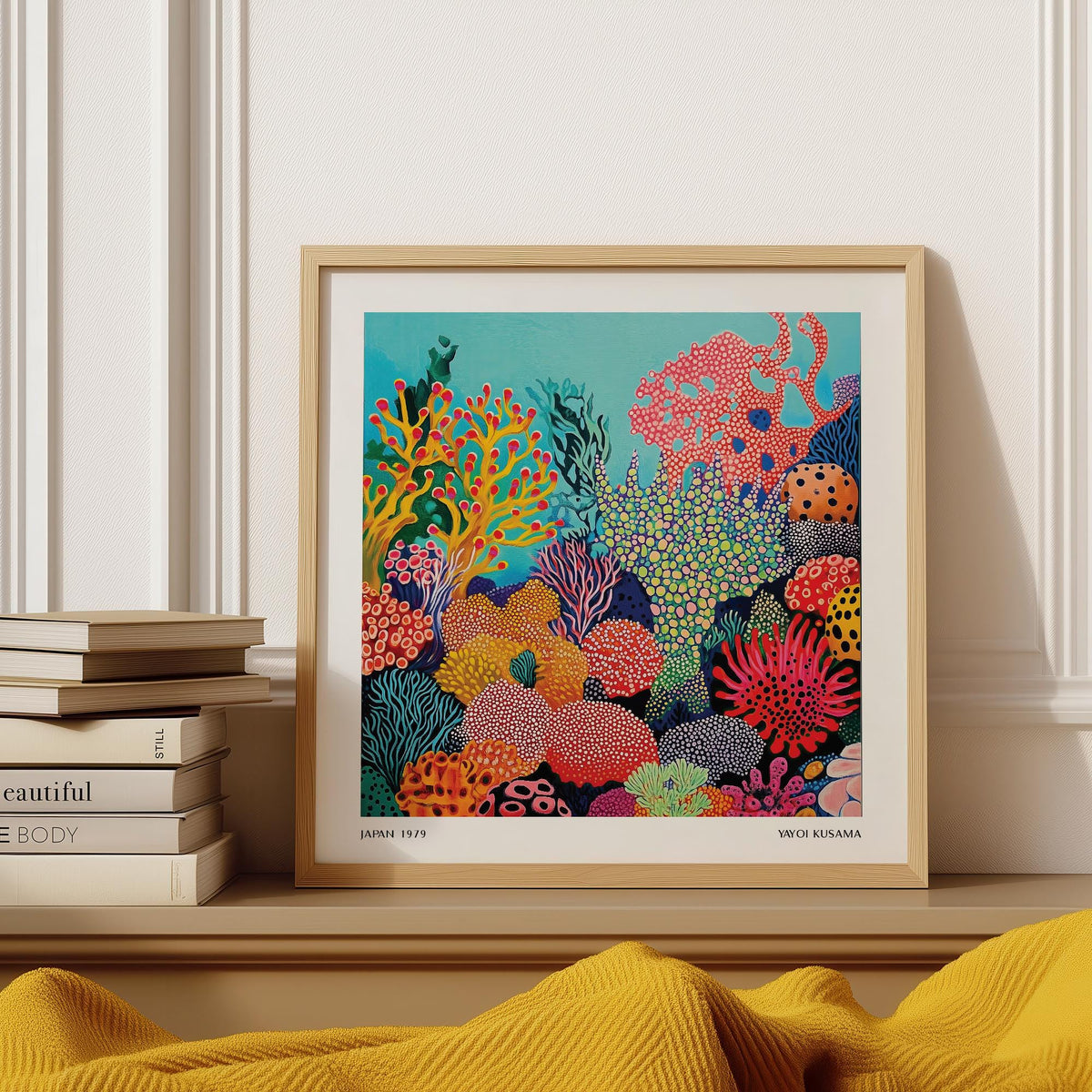 Tropical Sea wall art of an abstract colourful coral reef scene framed and resting on a beige surface with books nearby
