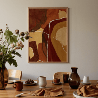 Abstract Earth Tones Print hanging above a wooden dining table with brown ceramics and a vase