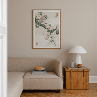 Owl Art Print in Japanese woodblock style with pale pink ginkgo leaves above beige sofa and wooden side table