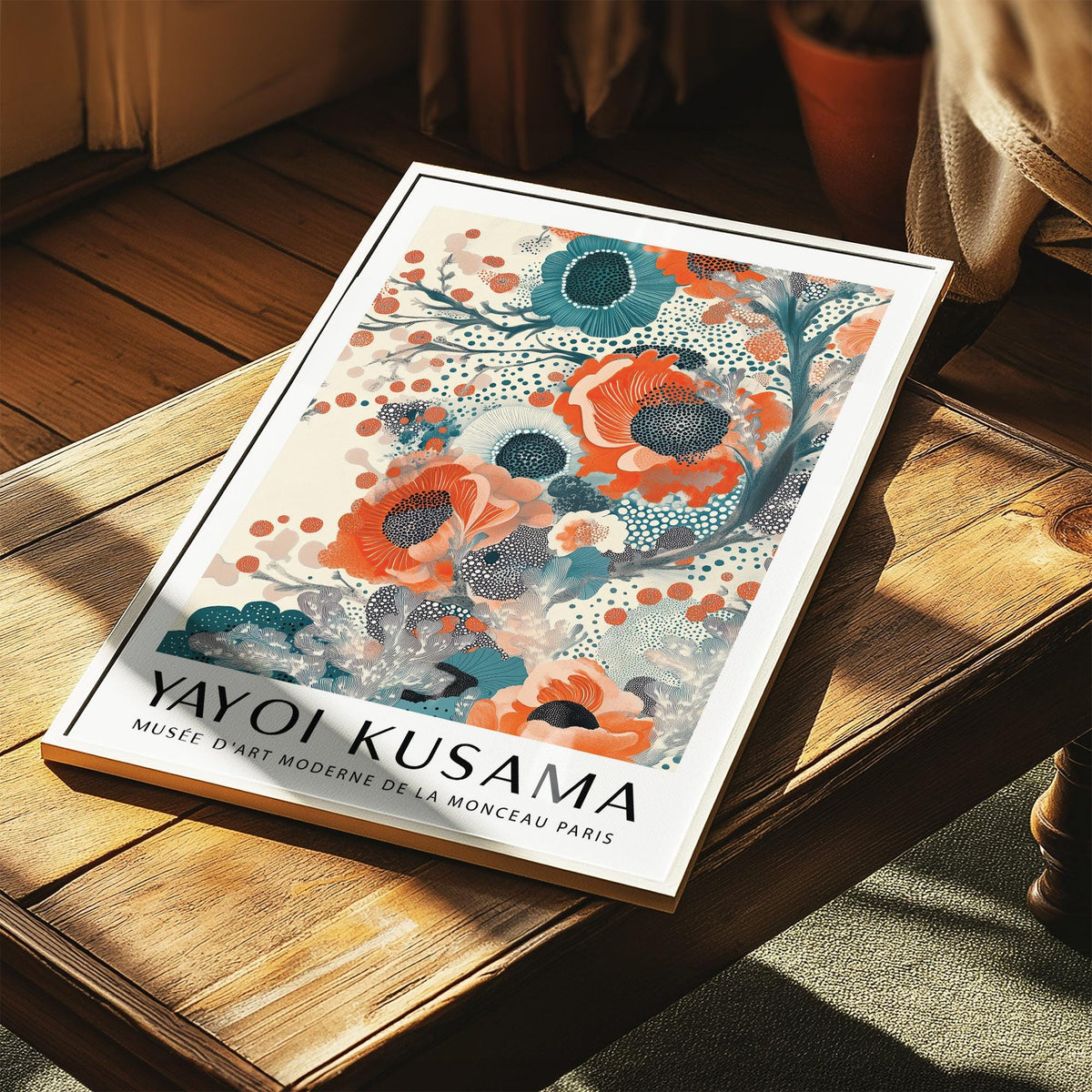 Framed teal and orange wall art with abstract floral blooms on a wooden table with a plant nearby