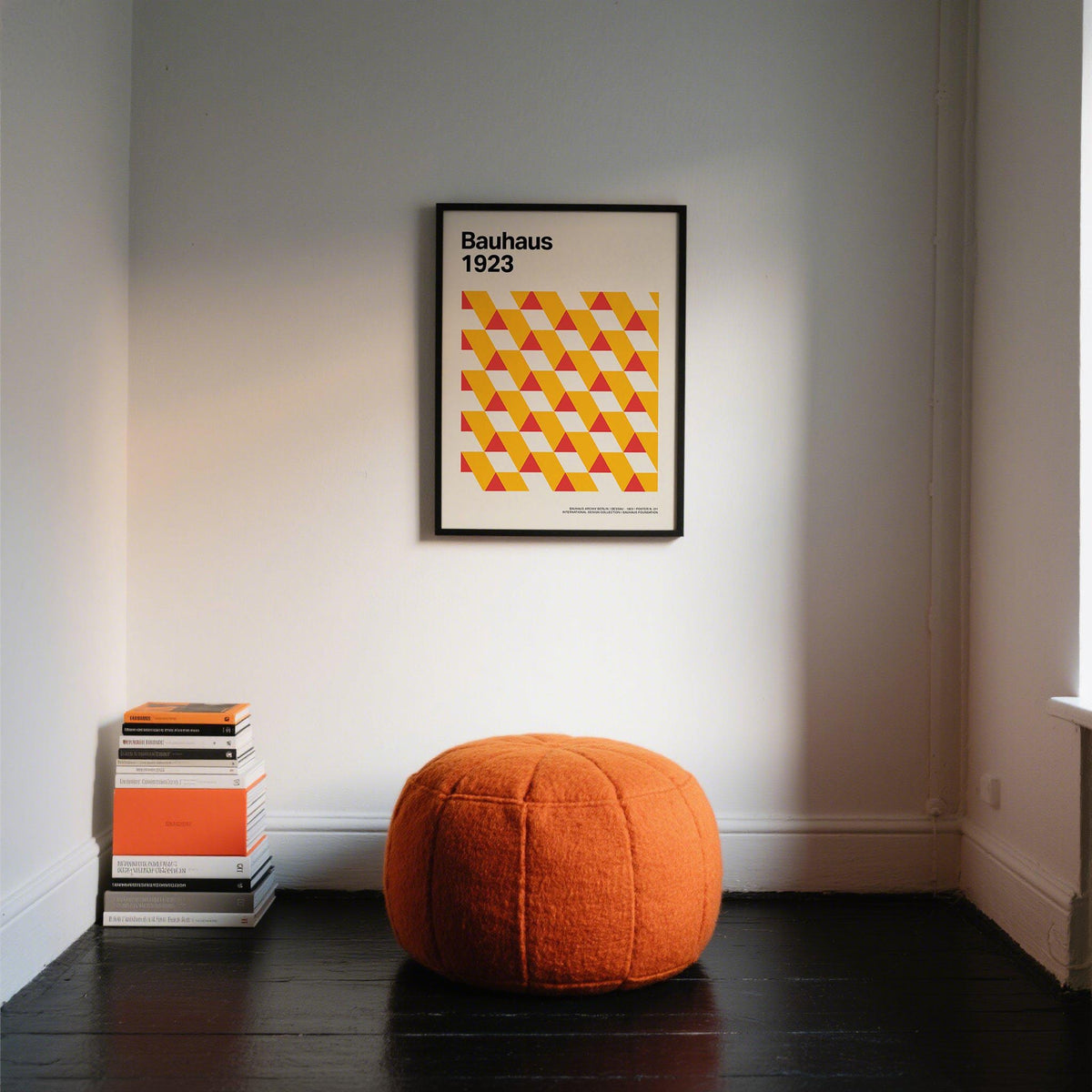 Art Posters Gallery framed print of yellow and red geometric triangles above an orange pouffe with stacked books