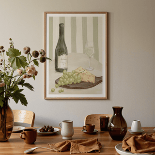 Elegant Dining Room Print of a white wine bottle glass and grapes hung above a table with crockery and a vase
