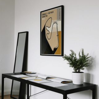 Sao Paulo Race Circuit Diagram Poster print on a wall with beige and black colours above a black desk with documents and a potted plant