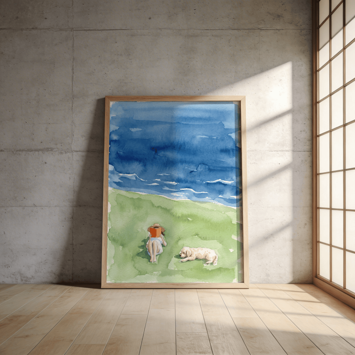 Reading By The Sea Art Print leaning on a floor against a sunlit concrete wall in a room with wooden floor