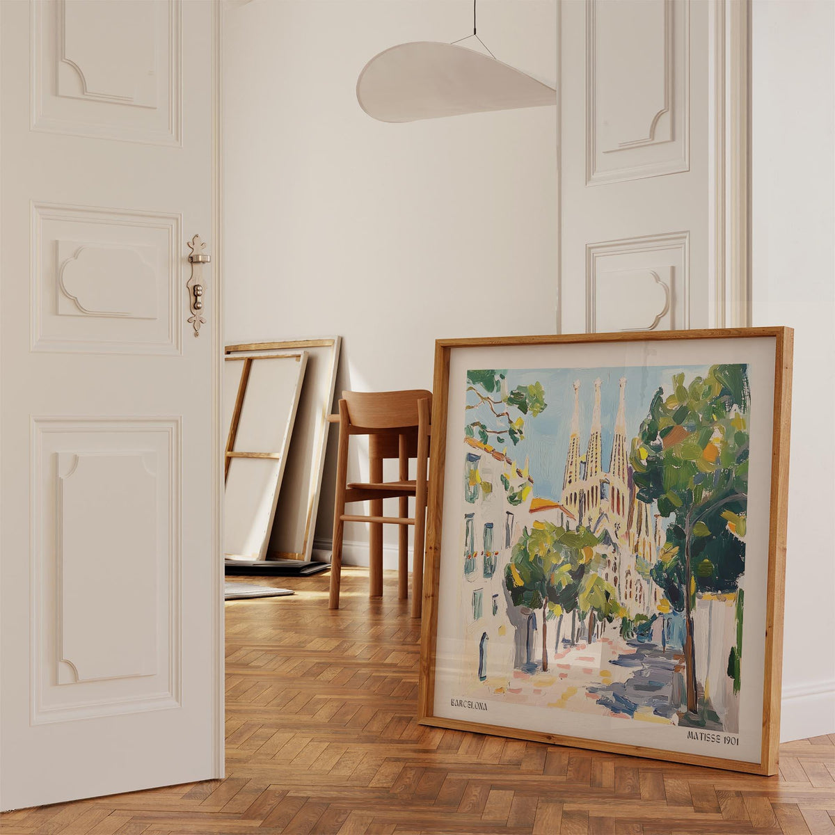 Print leaning on a floor showing Sagrada Familia with green trees in light pastel colours in a bright room