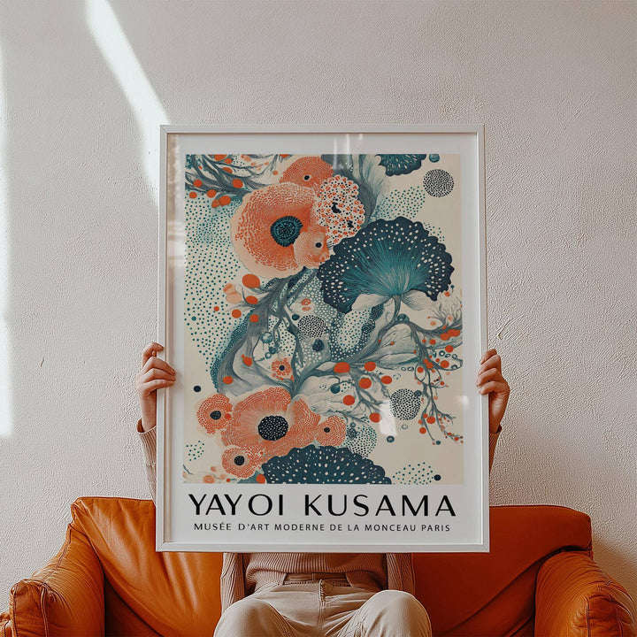 Abstract Floral Poster held in hands with stylised orange and teal flowers above a tan leather armchair