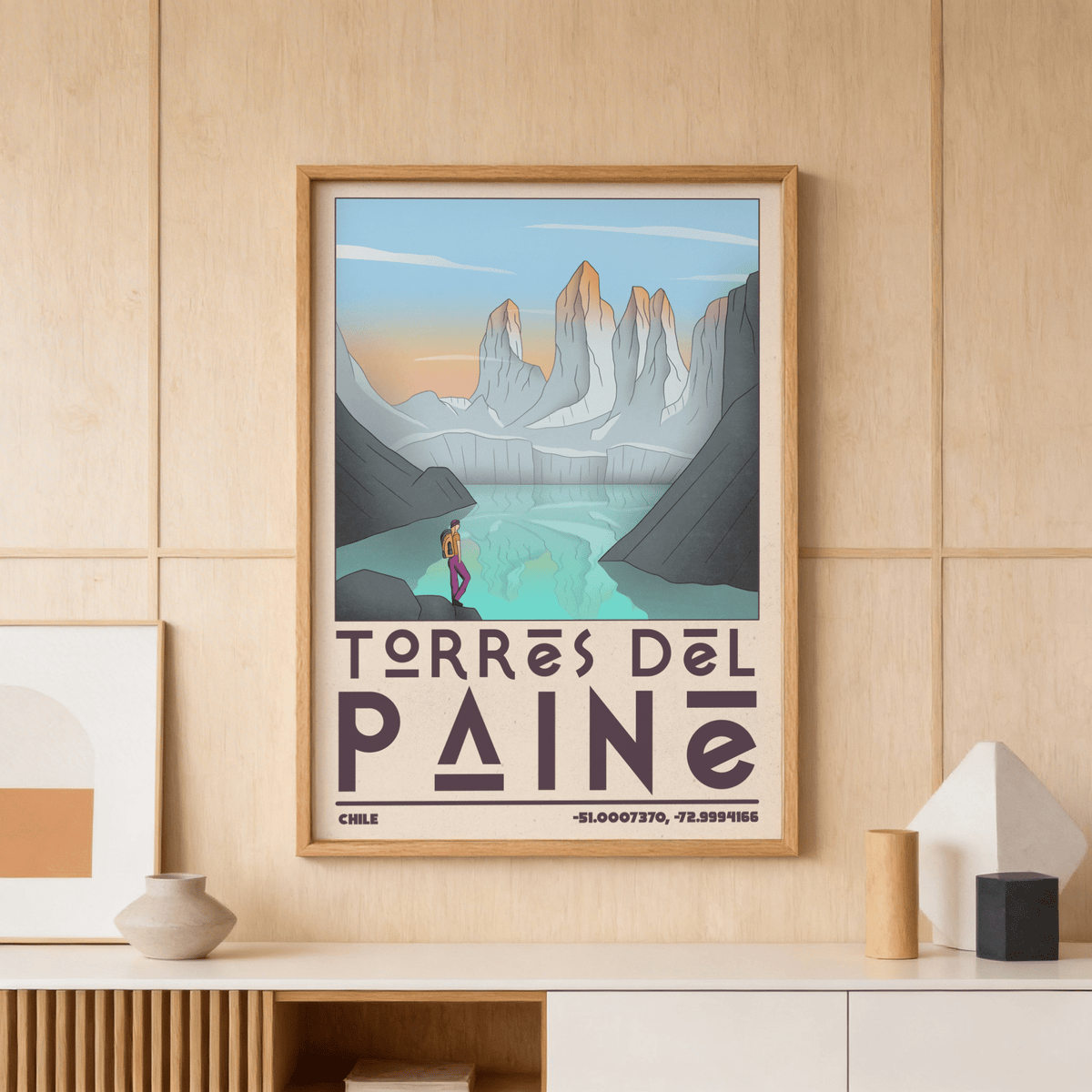 Torres Del Paine art print of mountains and lake in blue and orange tones on a wooden wall above a shelf with pottery