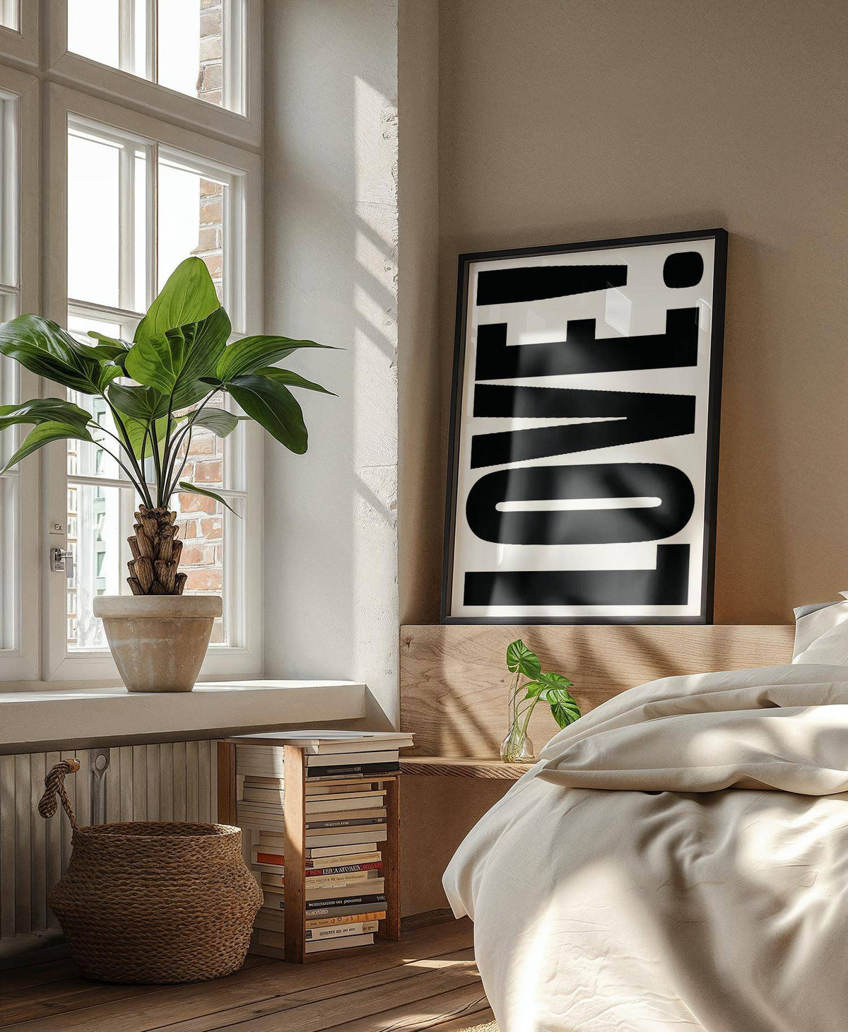 Large motivational posters leaning print with black LOVE typography and white background by a bed