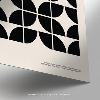 Close-up of black geometric shapes on off-white matte paper with text below