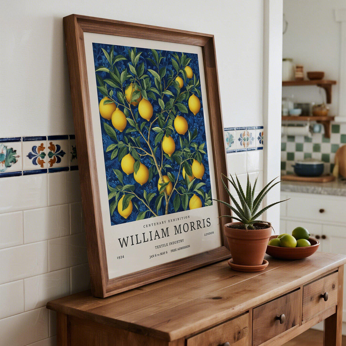 Lemon wall art framed print with a lemon branch illustration on a wooden surface near a plant pot and bowl of fruit
