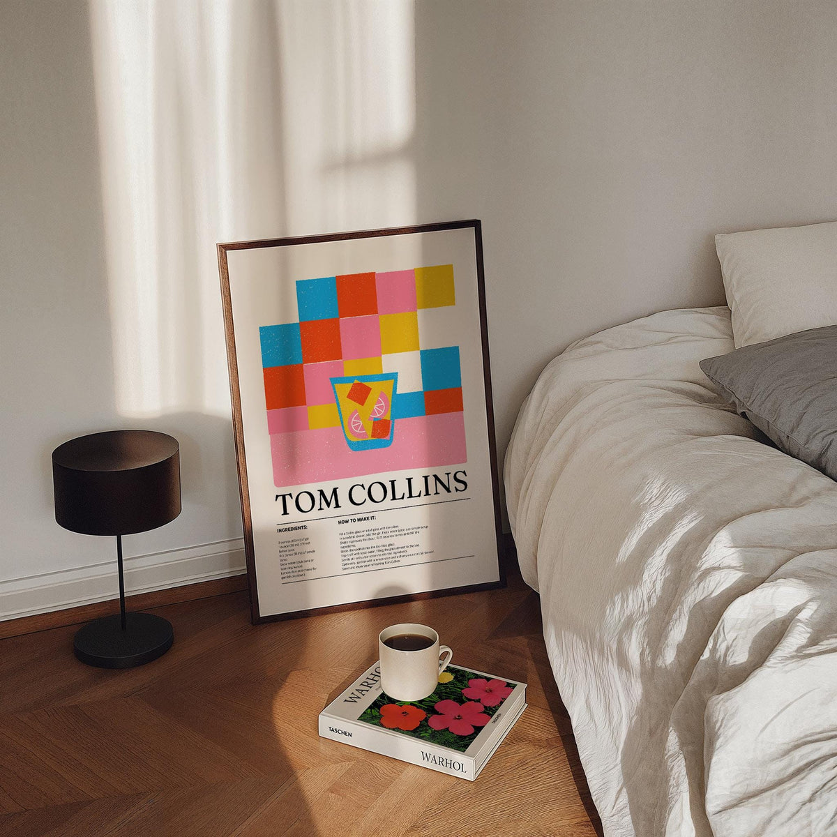 Colorful Bar Prints leaning print with minimalist pink blue and yellow cocktail illustration near bed and book