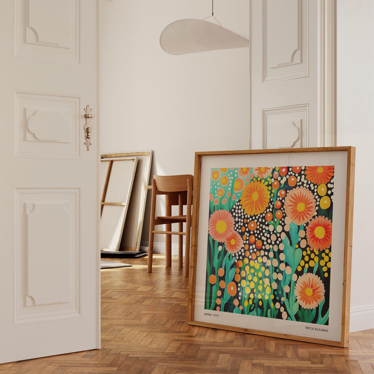 Print leaning on floor colourful flower art with orange and pink blooms in a bright room with chair