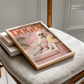 Framed Pink Poodle Print leaning on a stack of books on a chair with a wooden back