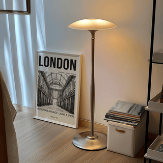 Print leaning on floor showing Victorian arcade interior in black and white beside a lit floor lamp