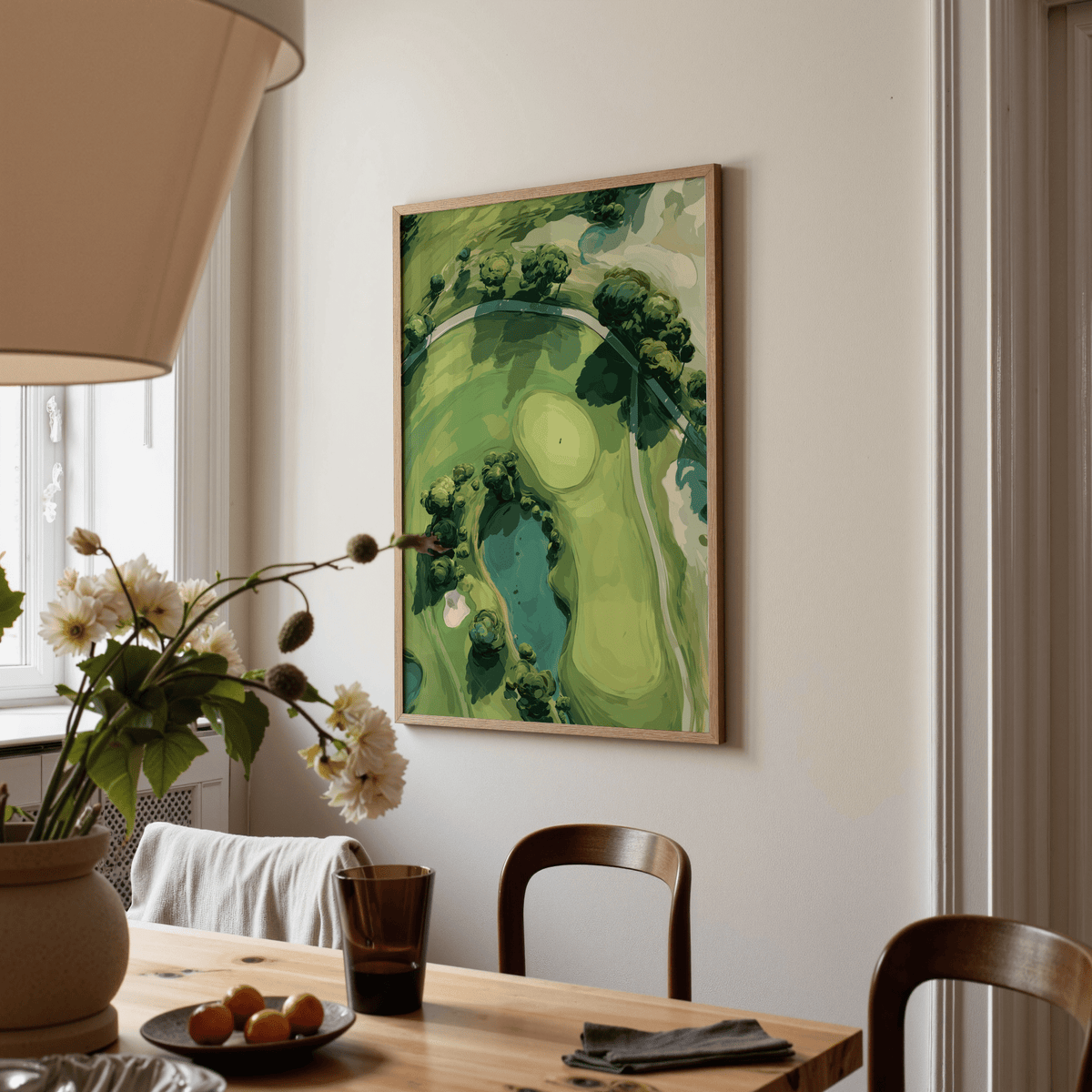 Print on a wall of aerial golf landscape poster in green shades beside a dining table with flowers
