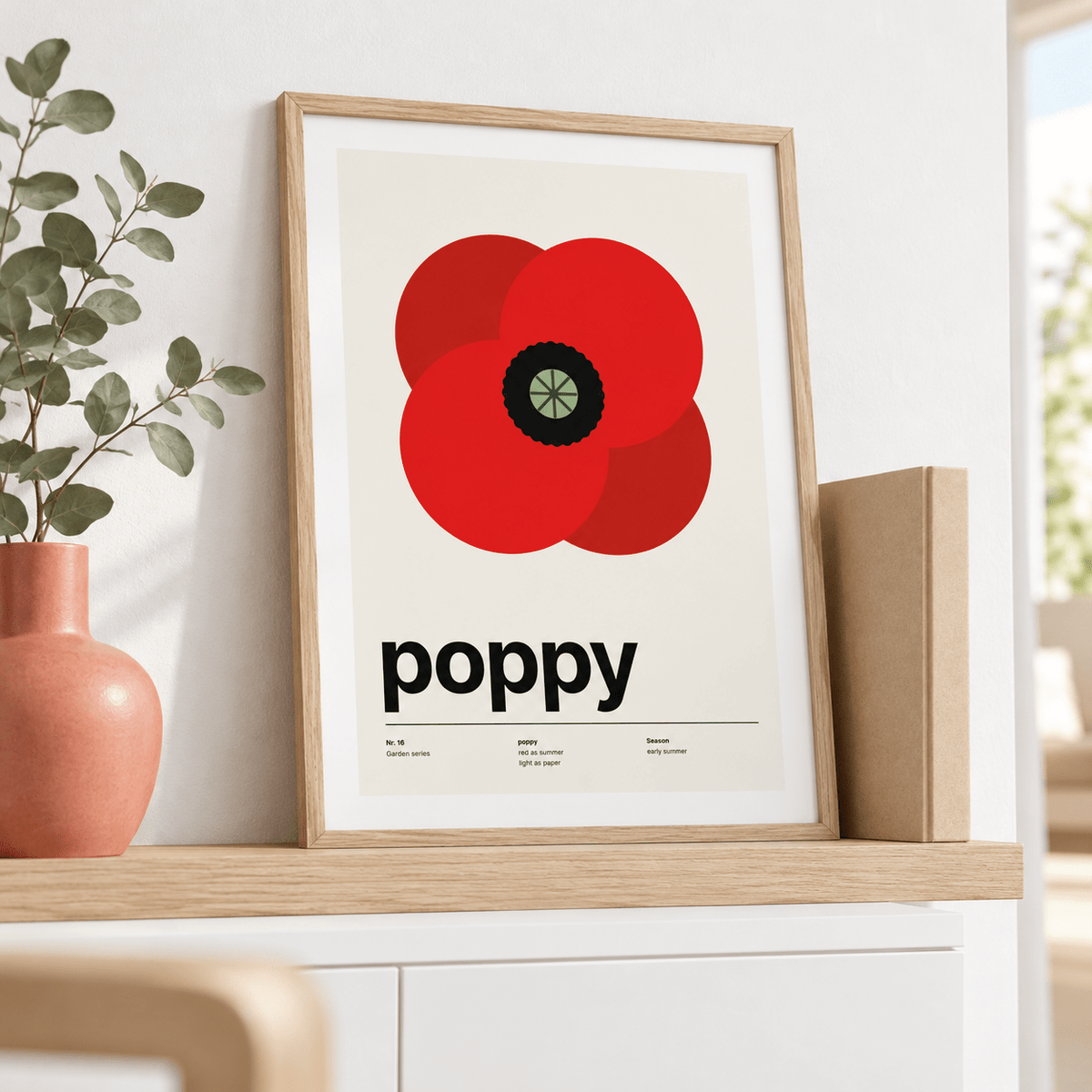 Swiss style poppy print leaning on a sideboard beside a pink vase