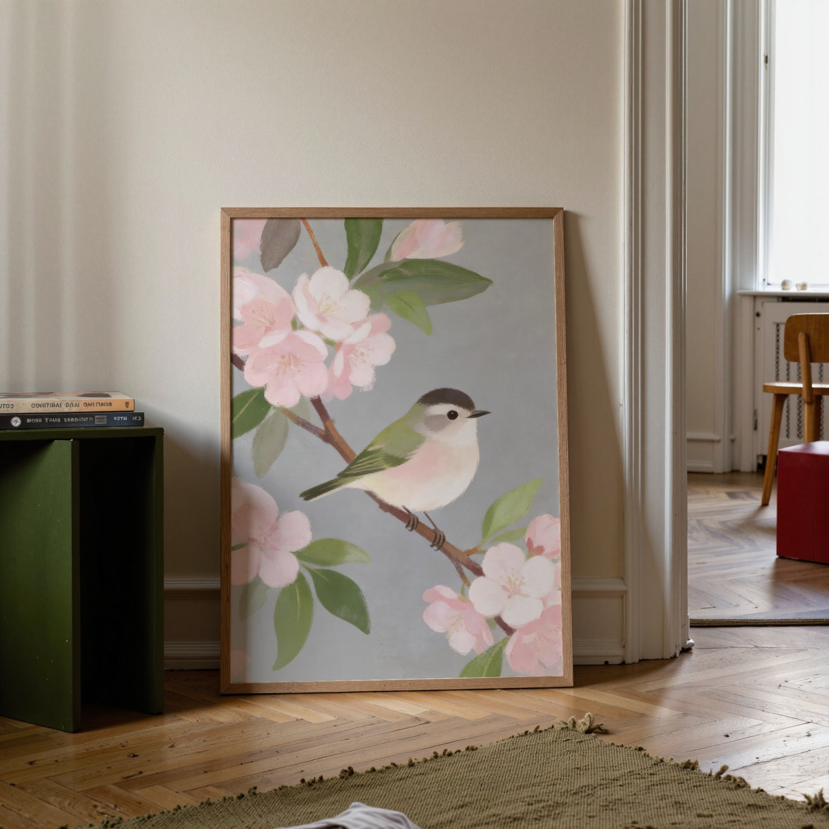 Print leaning on a floor with botanical bird wall art of a small bird on a branch with pink blossom