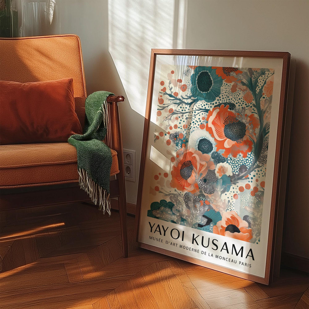 Teal and Orange Wall Art leaning on the floor beside an orange armchair with a green throw