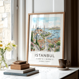 Framed Istanbul wall art of a watercolour cityscape by a window with books and a cup nearby