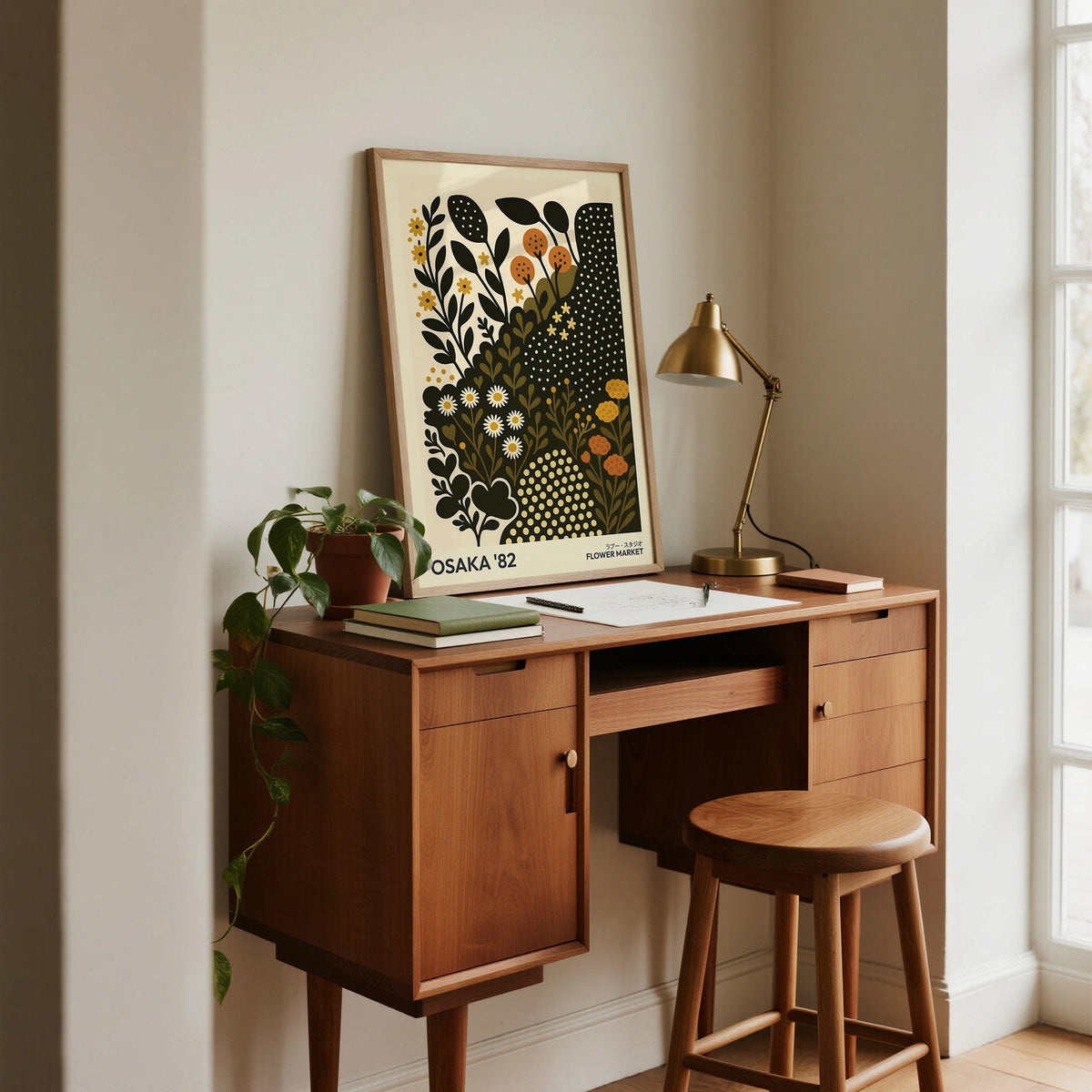 Daisy Art Print leaning on a wooden desk with a brass lamp and a climbing plant in a bright room