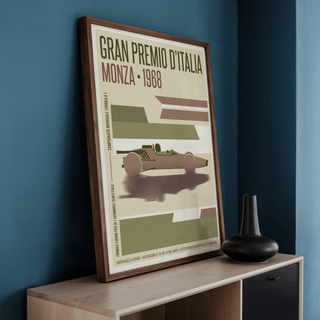 Framed Monza Grand Prix Poster leaning on a wooden shelf with a dark ceramic vase nearby