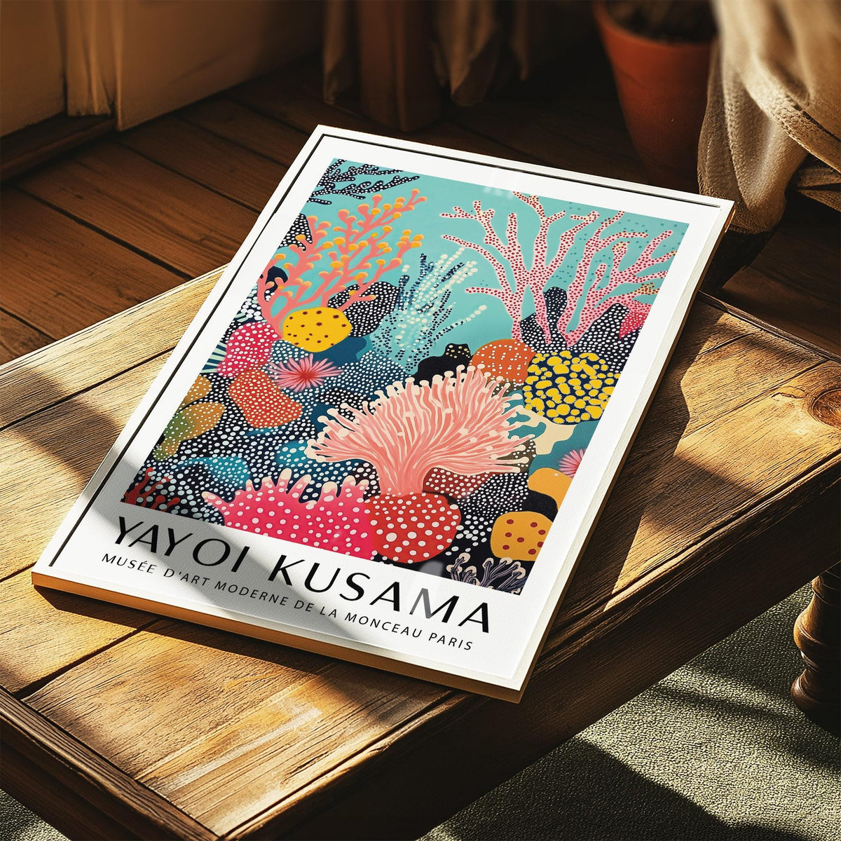 Bright wall art of an abstract coral reef print with vibrant blues and pinks leaning on a wooden table