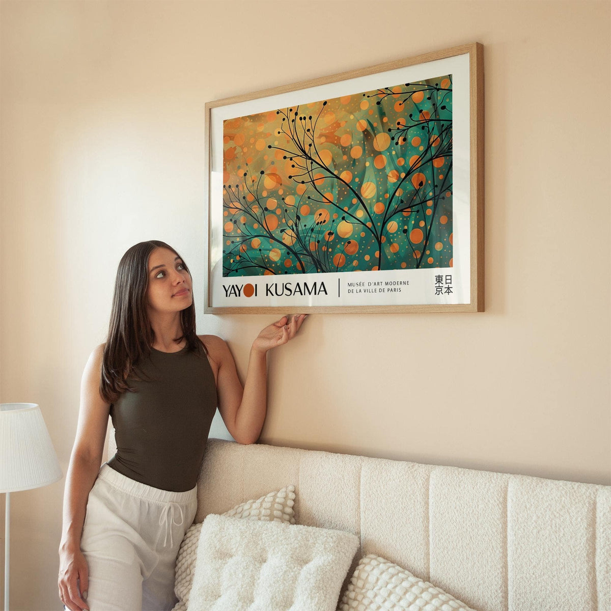 Autumn wall art of abstract autumn branches with orange and green hues hung above a cream sofa