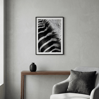 Zebra stripe art print close-up in black and white above a wooden console table in a grey room