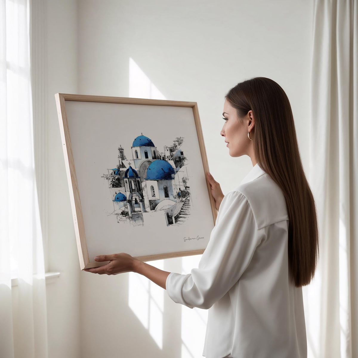 Framed Santorini wall art showing blue domed churches held by a woman in natural light