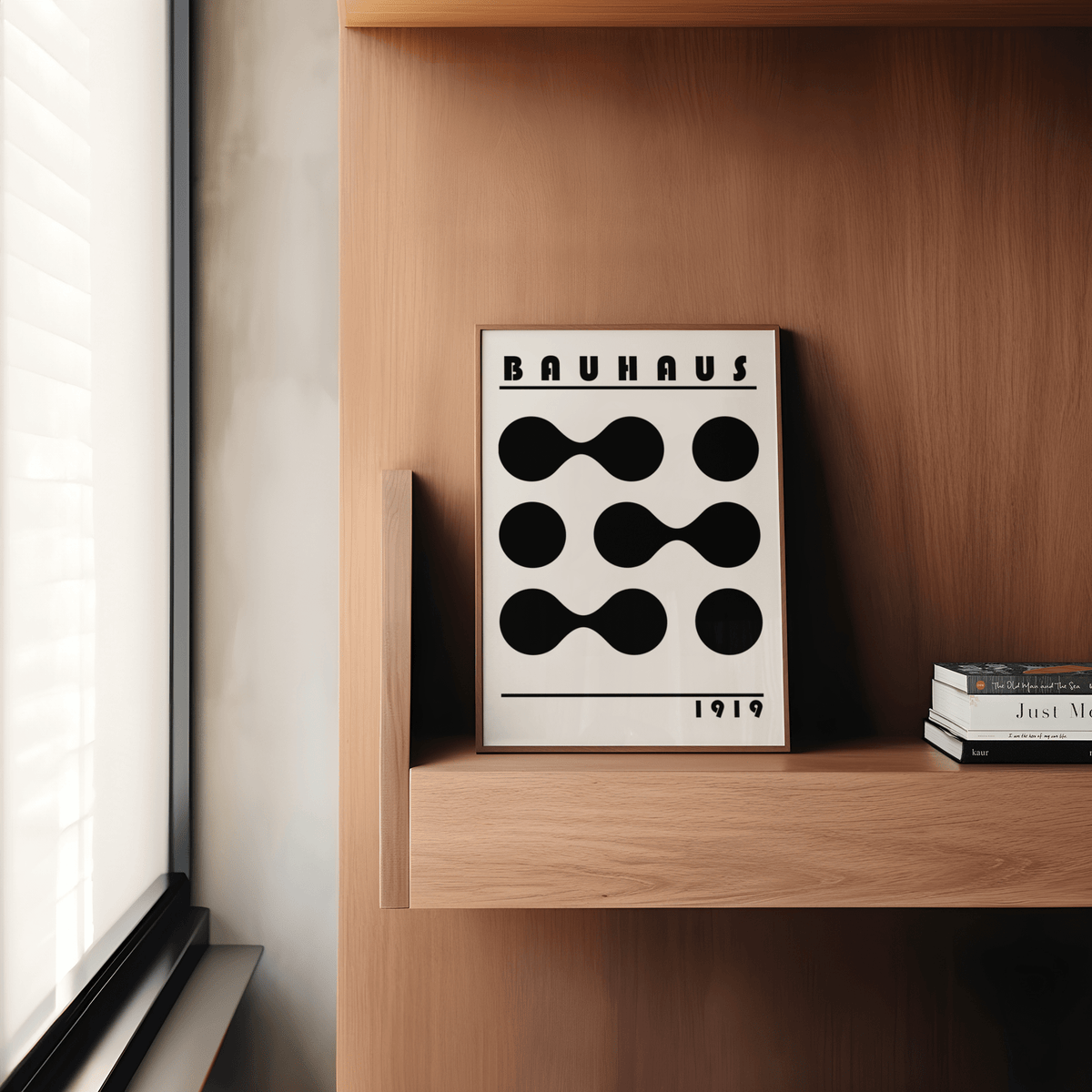 Framed Minimalist Geometric Print with black abstract shapes leaning on a wooden shelf by a window