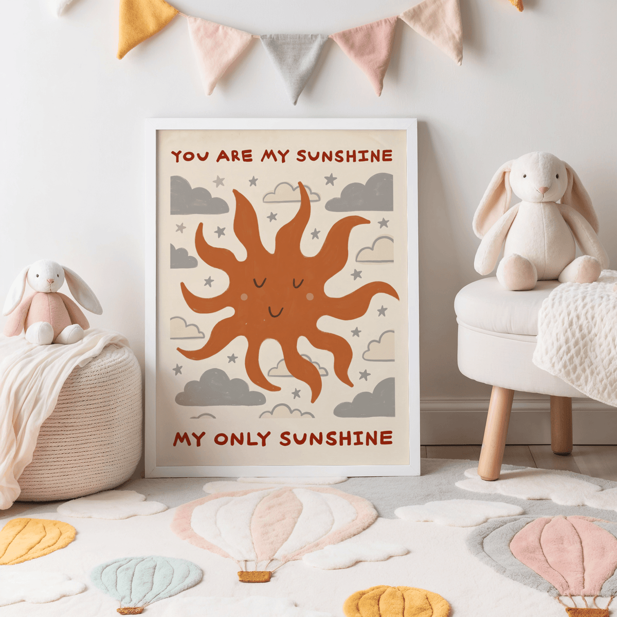 Print of smiling sun with clouds and stars in muted orange and grey colours in a child's room with soft toys