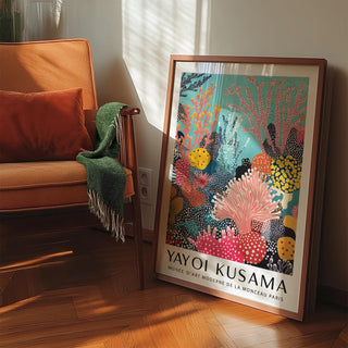 Bright wall art leaning on the floor with coral reef design in pink and turquoise next to an orange armchair
