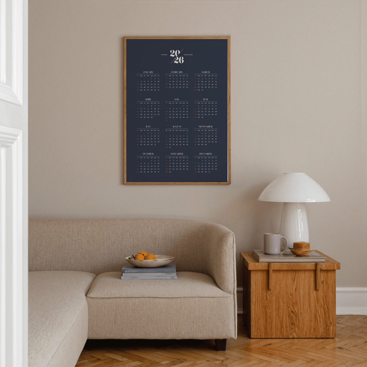 Minimalist Calendar wall art with a navy background and white text above a beige sofa and wooden side table