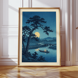 Moonlight Print leaning framed depicting a moonlit river scene in blue tones on a wooden floor