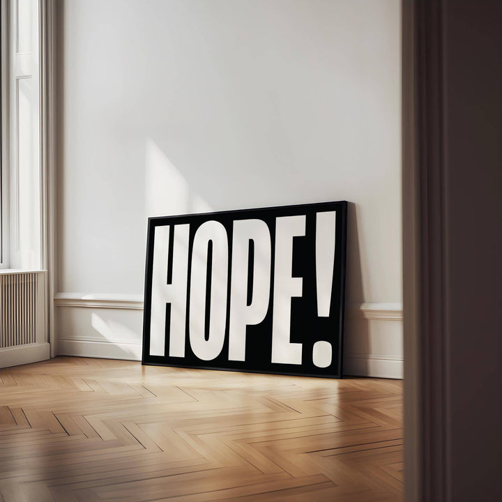 Inspirational Artwork leaning on a wooden floor with black frame and bold white text in a bright room