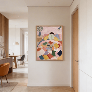 Woman Reading In Bed Art Print hanging on a plain white wall in a hallway with a wooden door nearby