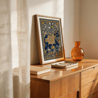 Indian art print leaning on a wooden dresser with jewellery tray and orange vase nearby
