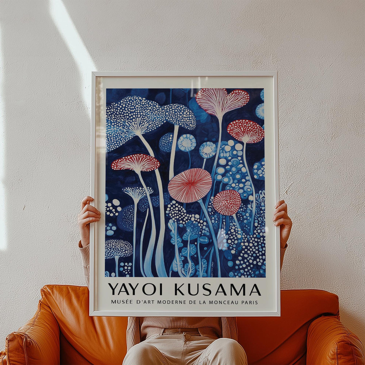 Framed Mushroom Art Print with red and white abstract mushrooms held above an orange sofa