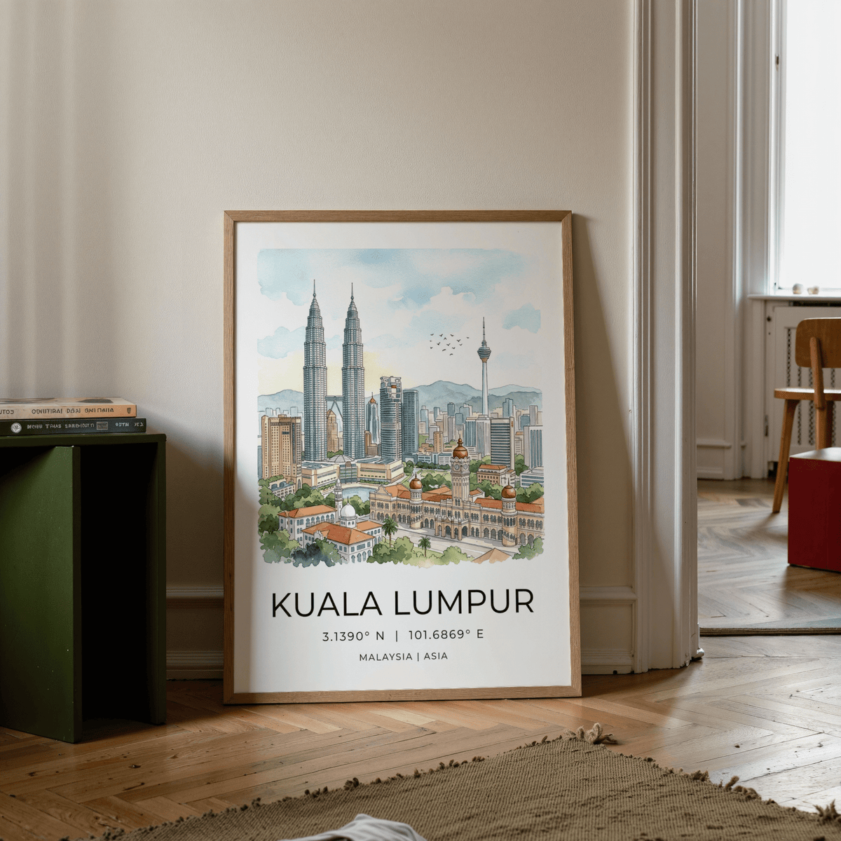 Print leaning on floor of Kuala Lumpur art print with beige wall and books on low green shelf