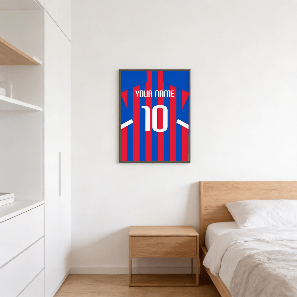 Print on a wall of football shirt poster in blue and red stripes above a wooden bedside table in a bedroom