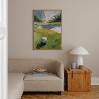 Golf Landscape wall art of a golf ball on a green fairway with a sand trap above a beige sofa