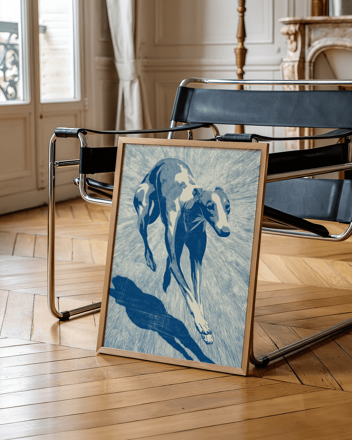 Print leaning on floor showing running greyhound illustration in blue and cream tones with black chair nearby