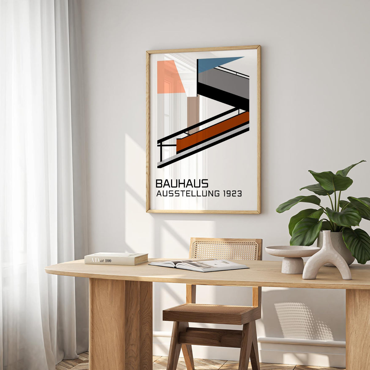 Bauhaus Exhibition Poster 1923 print with geometric shapes in muted colours on a dining room wall above a wooden table