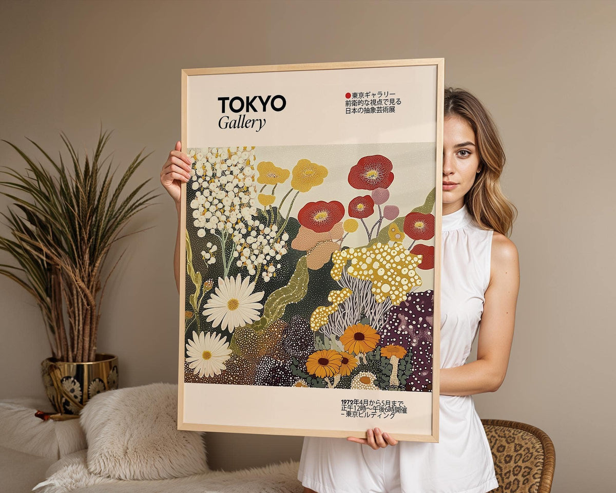 Framed Wildflower wall art held by a woman with stylised flowers in yellow red and white beside a plant