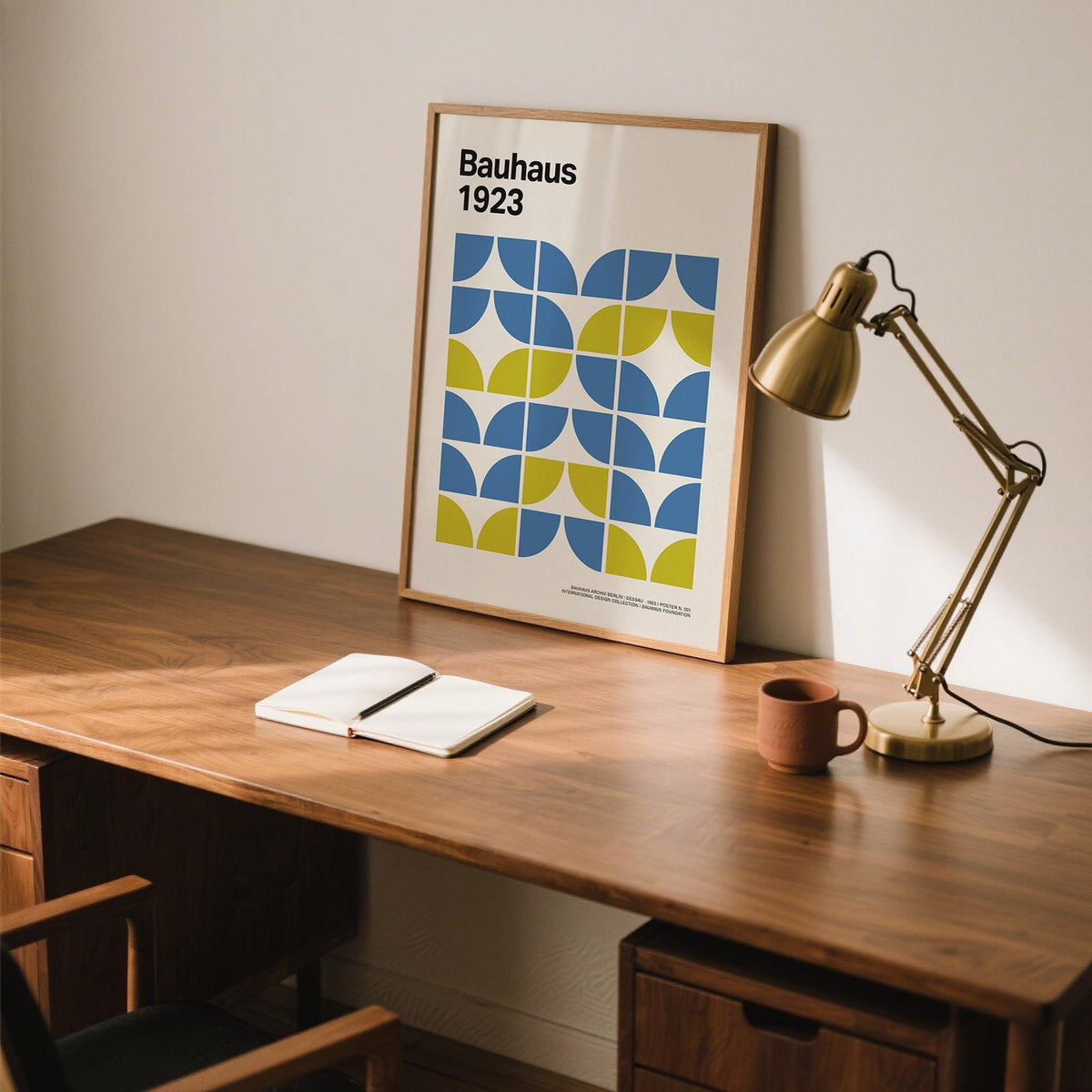 Modern Office Wall Decor print leaning on a desk with a brass lamp and an open notebook